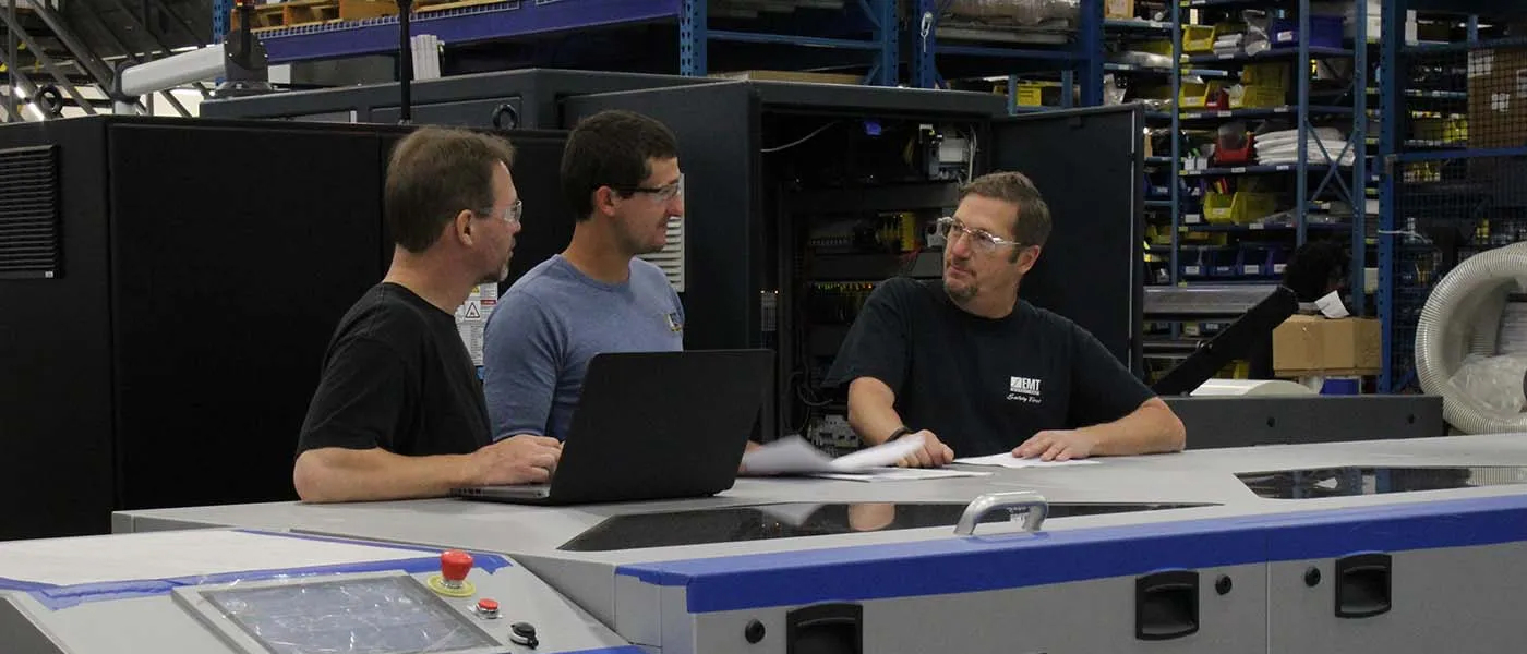 Three EMT employees meeting around a machine
